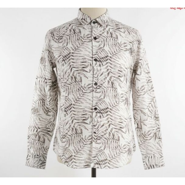White shirt with a repeating brown leaf pattern and a button-down collar