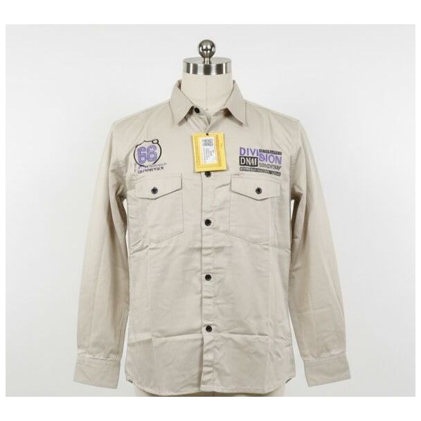 Beige cotton twill shirt with embroidered patches, button-up front and long sleeves.